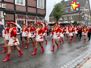 Rot-weiß gekleidete Damen marschieren im Gleichschritt und in Formation über die Rathausstraße.