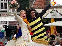 Bürgermeister Andreas Sunder steht als Biene verkleidet gemeinsam mit Prinzessin Carina I. Pahlsmeyer auf einem Karnevalswagen, der durch die Rathausstraße fährt.