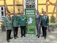 Die in der Bildzeile genannten Personen stehen vor dem Alten Progymnasium. Die Hausfassade besteht aus Fachwerk. Die Vertreter der Schützen tragen Uniformen. Alle Personen schauen in die Kamera.