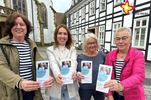 Katrin Dechange, Swetlana Reimer sowie Brigitte Schick und Christa Peitz steheh nebeneinander vor dem historischen Rathaus und halten je einen Flyer in Richtung der Kamera.