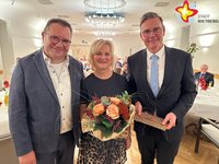 Der scheidende Beigeordnete Andreas Göke mit seiner Frau Ulla und Bürgermeister Andreas Sunder (von links) stehen im Ratssaal. Ulla Göke hält einen Blumenstrauß in den Händen.