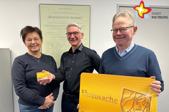 Doris Vogel, Jürgen Descher und Heinrich Rasche halten gemeinsam eine kleine und eine überdimensionale Ehrenamtskarte in den Händen.