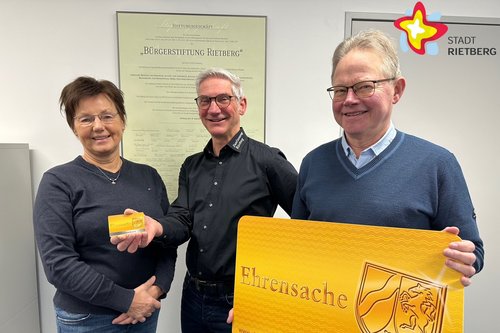 Doris Vogel, Jürgen Descher und Heinrich Rasche halten gemeinsam eine kleine und eine überdimensionale Ehrenamtskarte in den Händen.