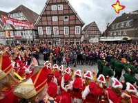 Das Foto zeigt einen Blick auf die Rathausstraße. Karnevalisten in Gardeuniformen feiern gemeinsam mit Besuchern.